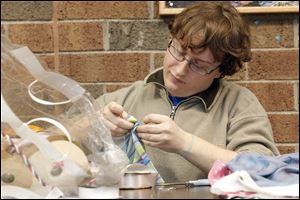 Zack Doane, a theater major, applies ribbon to a pillowcase that he is making into a dress for a resident of earthquake-devastated Haiti. 
