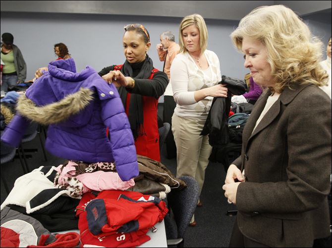 Kelly Marable, a day-care caseworker for Lucas County Children Services, left, elects coats for her clients Tuesday with the help of Kroger Co. employees Jackie Siekman and Kathy Smith, right, at the Children Services building on Adams Street. 