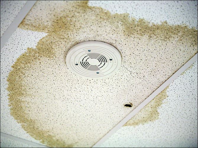 Water from a leaking roof at the new Rogers High School has dampened a section of ceiling tile in an office. A small hole allows water to drain into a waste bin.