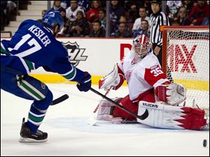 Detroit Red Wings goalie Jimmy Howard, right, stops a shot by Vancouver Canucks' Ryan Kesler during the first period.