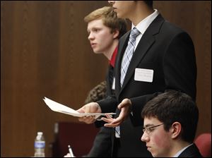 Sylvania Southview student Chris Ellis, left, objects to a question by St. John's Jesuit student John Banoub during the competition. Seated in the foreground is Harry Thaman of St. John's Jesuit. Two teams from  Southview advanced to the regional meet, as did one each from Perrysburg and St. Ursula.
