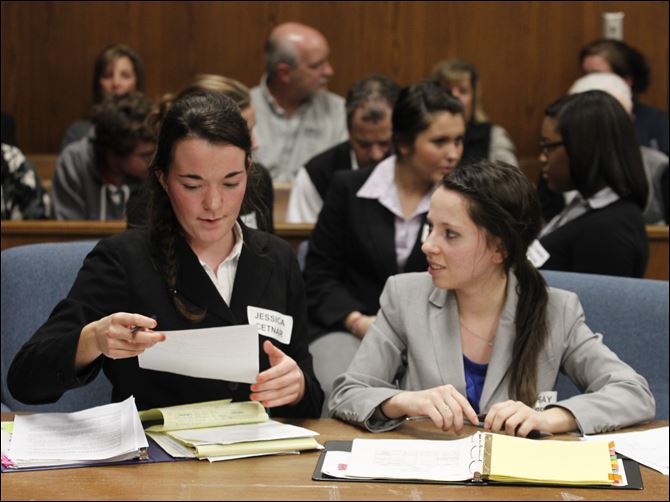 St. Ursula students Jessica Cetnar, left, and Lindsay Carr, both acting as attorneys, review their case in the courtroom.