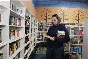 UT graduate student Caitlin McCallum, 24, looks over books at Ukazoo, a new bookshop on Westwood in Toledo. She says walking through a bookstore is a "better book experience."