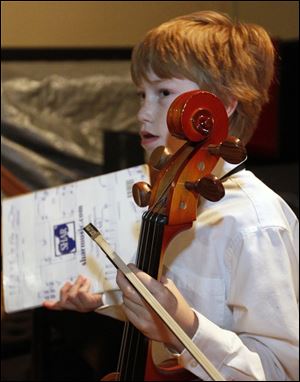 Oliver Durham, 11, a fifth grader at Ft. Meigs Elementary School, with his violin. The Toledo Symphony Youth Orchestra in performance at the Peristyle at the Toledo Museum of Art.