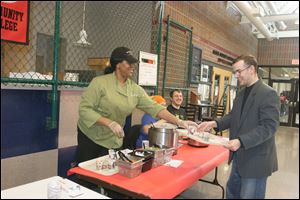 India Harris, left, of Jaguar Grill serves John Kilmer during the Owens Community College chili cook-off.