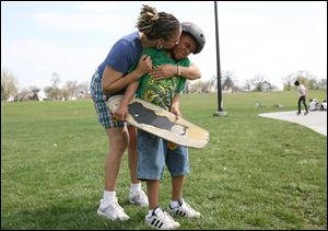 Shaun Purley plants a kiss on her son, Jordan, before he heads off to the skateboard area at Highland Park.