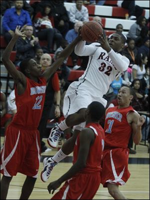 Bowsher's Kharri Dailey shoots in front of Rogers' Keandre Gilmer (21) and Tribune Dailey during first half at Rogers High School in Toledo, Ohio.