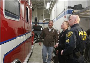 Jeffrey Howard of Owens Community College, left, talks with Perrysburg police Officer Joe Ball and Lake Township Sgt. Scott Sims about Owens students helping to convert a Perrysburg Township ambulance into a SWAT vehicle. 