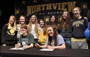 Northview High School cross country teammates Maureen Dean, seated left, and Alison Work, seated right, pose with teammates after sign their national letters of intent to attend their respective colleges, during a ceremony at Northview.  Dean will attend Ohio University and Work will attend Grand Valley State.  Teammates standing from back left are Abby Masters, Katelyn Work, Robin Foster, Laura Judge, Mallory Small, Morgan Vince, Esther Haviland.