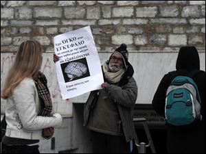 At a metro station in Athens, a man displays a banner reading 'I have a brain tumor -- I'm jobless and homeless' as anger mounts at prospects of more economic pain.