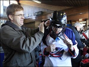 Joe Witalec helps his son Joshua, 14, a player on the team dubbed the Columbus Blue Jackets, with his gear before taking the ice. The first day of a round-robin tournament was Saturday.