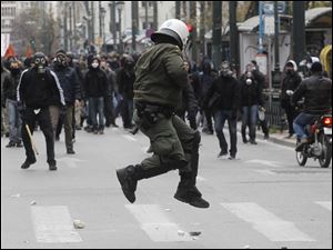 A policeman in riot gear tries to avoid a stone thrown by a protester during clashes in Athens,  where at least eight officers and two members of the public were injured. At least six people were arrested.