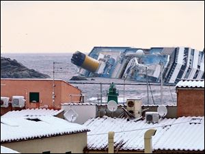 Snow covers the rooftops of the houses overlooking the harbour of the Tuscan island of Giglio, Italy, Saturday as the grounded Costa Concordia cruise liner still lays stricken in background.