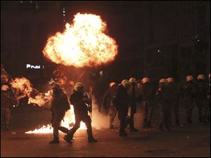 A petrol bomb explodes over riot police during clashes in Athens Sunday. Riots engulfed central Athens and at least 10 buildings went up in flames in mass protests late Sunday as lawmakers prepared for a historic parliamentary vote on harsh austerity measures demanded to keep the country solvent and within the eurozone. 
