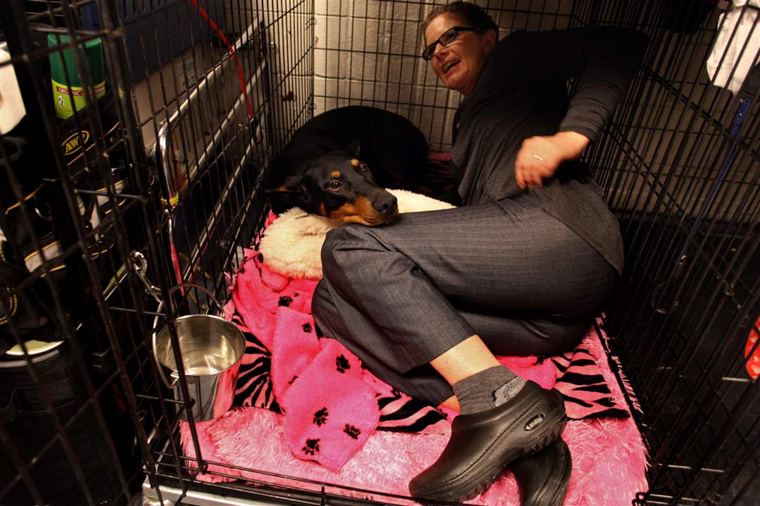 Fifi-a-doberman-pinscher-is-joined-in-her-cage-by-co-owner-Suzy-Lundy-of-Oregonia-Ohio