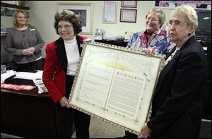Trudy Urbani, left, of the Century House Preservationists, accepts the plaque from Pastor Sarah Richey of Hampton Park Christian Church, center, and Deanna Farran, elder. The plaque bears a hymn written by Ina Duley Ogdon, 'Brighten the Corner Where You Are.' The plaque will be displayed in Mrs. Ogdon's Lambertville cabin.