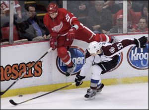 The Detroit Red Wings' Kyle Quincey (27) goes up against the boards to chase the puck against the Avalanche's Cody McLeod.