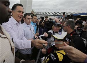 Republican presidential candidate, former Massachusetts Gov. Mitt Romney signs autographs for fans as he visits Daytona International Speedway on Sunday. The race was postponed for the first time ever because of rain and will be held on Monday.