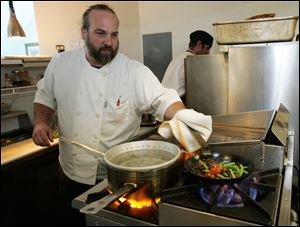 Chef Michael Bulkowski sautes green beans and cherry tomatoes for his halibut dish at his restaurant, Revolver. 