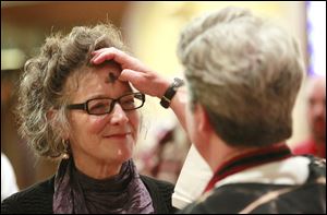 Joan Fothergill, left, from Toledo, receives ashes from Trinity Episcopal Church's rector the Rev. Elizabeth Hoster, right, during the the Ash Wednesday service.