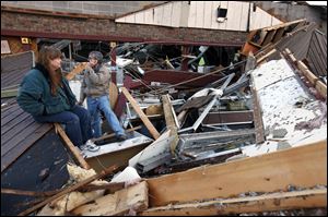 Sherry Cousins and her brother Bruce Wallace of Hollister, Mo., sit in the wreckage of their secondhand store in Branson, Mo, on Wednesday.