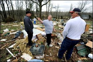 Steven Vaught, center, tells bystanders about having survived a harrowing ride inside his mobile home Wednesday morning when it flipped during a severe storm near Central City, Ky. Vaught said he thought his trailer flipped five times before he found himself outside several hundred feet from where his home had been minutes earlier.