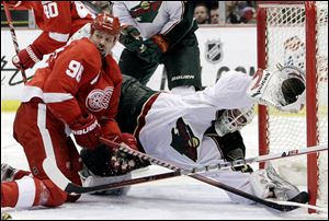 Minnesota Wild goalie Josh Harding (37) stretches to stop a shot on goal next to Detroit Red Wings left wing Tomas Holmstrom (96), of Sweden, during the third period of an NHL hockey game in Detroit, Friday.