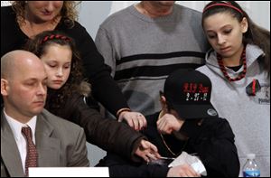 Domenic Parmertor, brother of Chardon High School shooting victim Daniel Parmertor, is comforted by family members during a news conference in Eastlake, Ohio. The Parmertor family and relatives of other victims met with the media about Monday's shooting.
