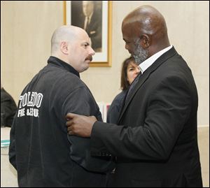 Mayor Mike Bell talks with Toledo fire Lt. Matt Tabb before a news conference Friday at One Government Center to announce that the city and the union representing its firefighters have reached a tentative agreement on a new contract.