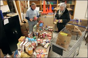 Steve Drake, Feed Your Neighbor worker, helps Tammie Huth select food at Augsburg Lutheran Church. Ms. Huth said she thinks politicians’ comments denigrating people in need of assistance are absurd. Perhaps, she added, those politicians think low-income people don’t vote.