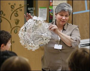 Artist Mary Gaynier, of Point Place, shows students at Ottawa Hills High School how to make paper snowflakes.