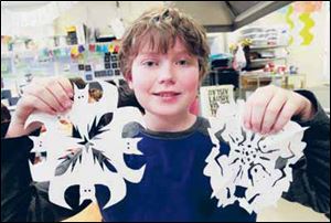 George Estes, 13, holds snowflakes he cut out.