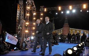 Russian President Dmitry Medvedev, right, and Prime Minister and presidential candidate Vladimir Putin arrive for a rally with supporters outside the Kremlin, seen in the background, in downtown Moscow.