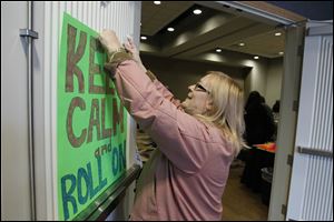Perrysburg's Sandra Alden, who relies on TARTA to get to work,  hangs a sign before a rally at the Hilton Garden Inn at Levis Commons in support of continued service.