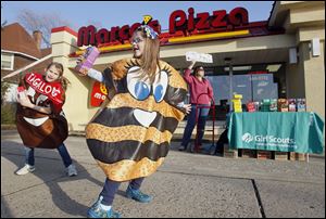 Left to right Grace Fite, 8, and Gabrielle Myers, 7, both of Perrysburg, Ohio, sell Girl Scout Cookies in front of Marco's Pizza Wednesday, 02/29/12, in Rossford, Ohio. in the background is Liz Fite holding up a sign.