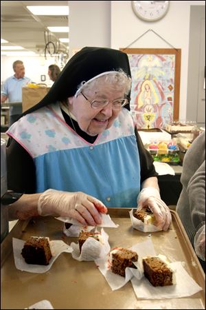 Louise Beauregard (right)  gets a tray of food during the 30 year celebration of Our Lady of Lourdes Hospitality Kitchen at the parish on 6149 Hill Ave.. She is being served by Sister 
