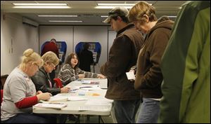 Poll workers Stephanie Hennigan, left, Diane markham, and Mary Kurtsz assist voters in Perrysburg, where city council hired a transit consultant last month.