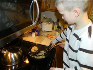 Ben Tucker flips the rice pancakes he and his mother, Lisa, created for the Uncle Ben's contest. The Highland Elementary student is among 500 finalists in the contest. The recipe called for cooked white rice, two teaspoons milk, two eggs, a dash of salt, and a handful of fruit.