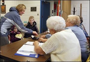 Chelle Bauder shows her identification under the watchful eyes of her daughter Grace, 2, and son Harry, 5, in Woodville Township. Poll workers helping her are, from left, Mary Restemeyer, Rae Curtis, and Margaret Schwartz.