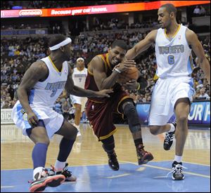 Cleveland Cavaliers guard Kyrie Irving (2) is fouled by Denver Nuggets guard Arron Afflalo (6) and Ty Lawson (3) during the second quarter in Denver Wednesday.