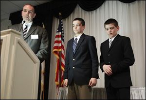 Erik Chappell, with his sons Grant, 14, and Cole, 11, at his side, accepts the Adult Good Samaritan Hero award from the Monroe County Chapter of the American Red Cross at a banquet in LaSalle, Mich.