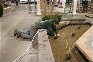Adam Kreinbrink of Acu-Turf Toledo prepares to fill the man-made stream that surrounds a floating patio with a reverse waterfall display for the upcoming Home Improvement and Garden Show.