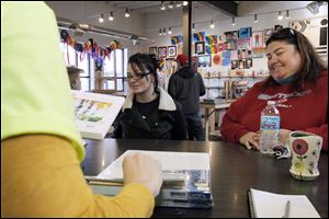 Tiana Katakis, 17, left, and her mother, Becky Jones, both of Lemoyne, Ohio, wait as their purchase is rung up by Dana Syrek at the Art Supply Depo on South St. Clair Street in downtown Toledo. The locally owned store was chosen by one of two local groups as a site of a ‘cash mob’ event Saturday, during which shoppers were asked to show support for area businesses by making a purchase.
