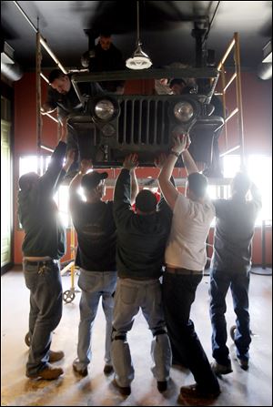 Workers install an original Jeep front end at the Ye Olde Durty Bird, which is making a return to downtown Toledo. The owners say the establishment on South St. Clair Street is focusing on Toledo's history when it comes to decorating the interior of the building.