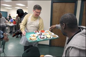 Dennis Linn serves Douglas Graham a dessert at St. Paul's Community Center in Toledo. 