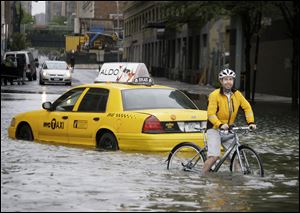 A bicyclist making his way past a stranded taxi on a flooded New York City Street as Tropical Storm Irene passes through the city in August, 2011.