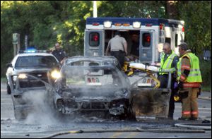 A Monroe firefighter sprays water on the burning car of Erik Chappell in this Sept. 20, 2011, file photo.