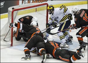Michigan's Luke Moffatt (9) puts the puck in the net during a scrum 1:04 into the second overtime against Bowling Green to beat the Falcons 3-2.