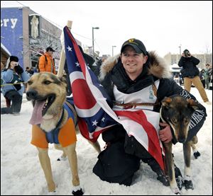 Matt Failor, a Mansfield native and Ohio State graduate, prepares for the start of the Iditarod while holding an Ohio flag. his father, Tim, graduated from Rossford High School, and his mother, Cheryl, graduated from Notre Dame Academy.
