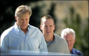 NFL football quarterback Peyton Manning, center, takes a tour with executive vice president of football operations for the Denver Broncos John Elway, left,  and Broncos coach John Fox, rear right,  at the Broncos' training facility in Englewood, Colo.